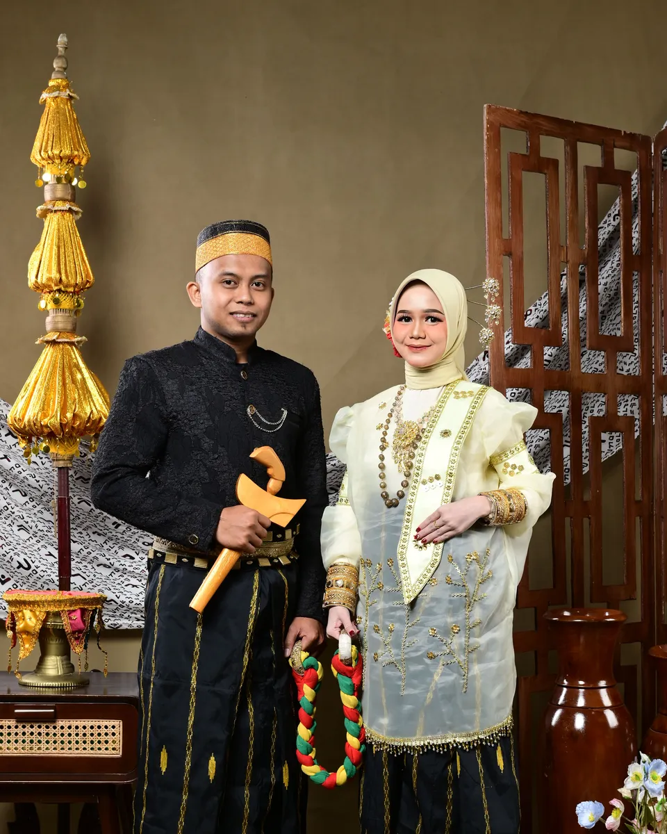 Indra dan Asdar berdiri bersama dalam busana adat